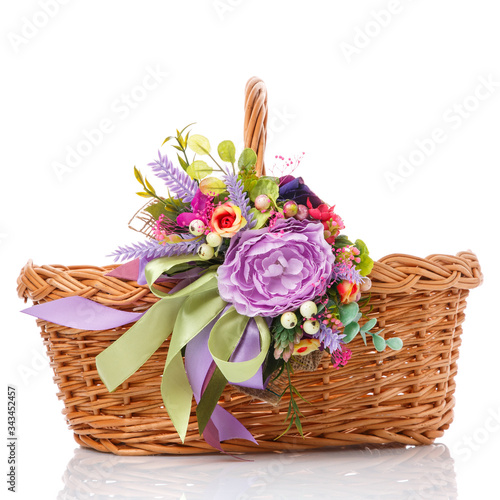 Wicker basket decorated with colorful flowers and ribbons. Isolated