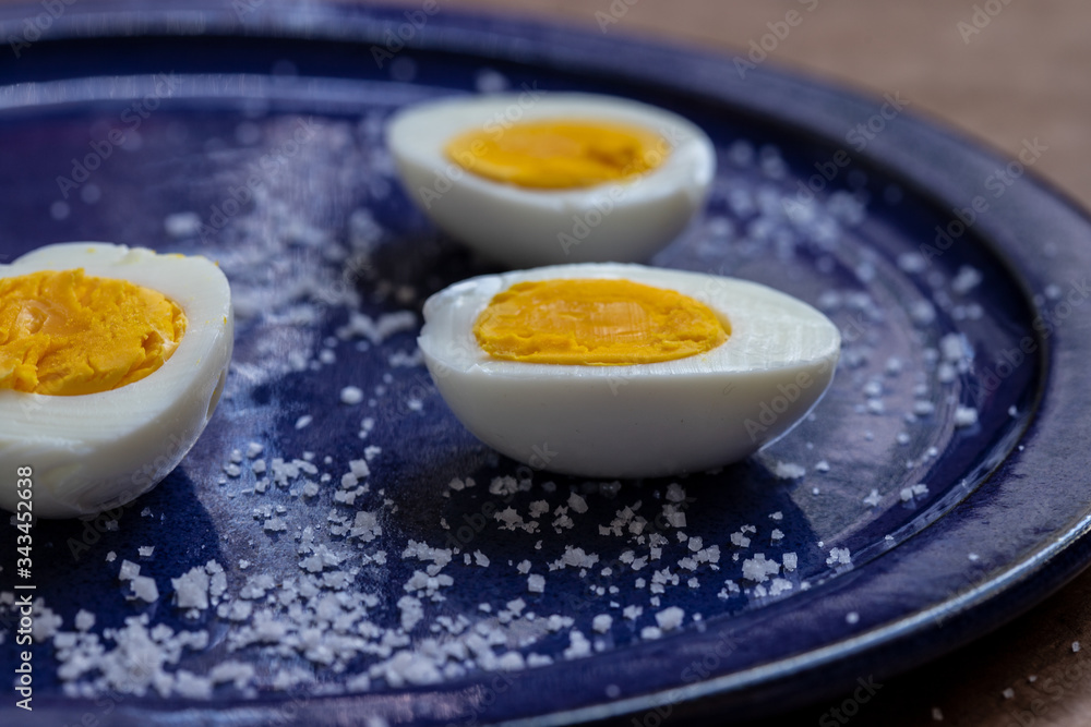 three half eggs on a blue plate with salt three half eggs on a blue plate with salt
