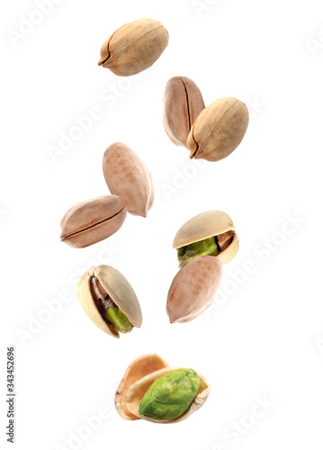 Tasty pistachio nuts falling on white background