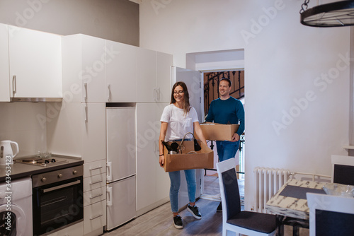An attractive caucasian man and woman are entering a new apartment with boxes of things. A loving couple moves in © Dragica
