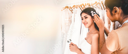 Bride in a wedding dress with a young female friend who is dressing for