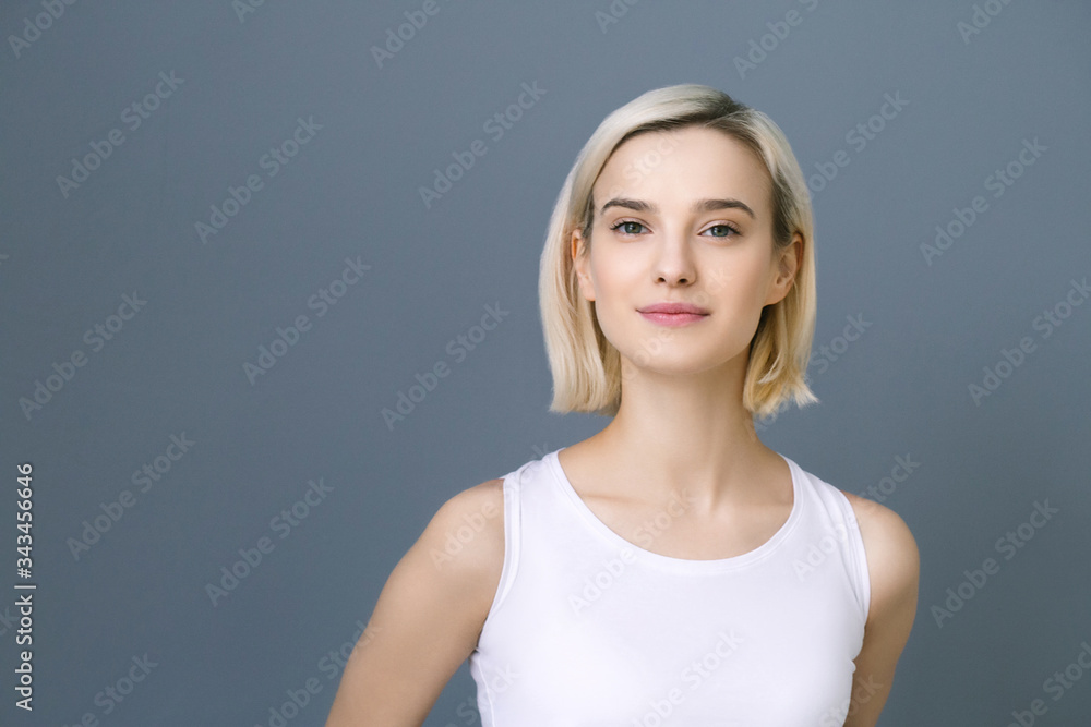 Beautiful woman blonde short hair natural casual make up over gray wall Beautiful woman blonde short hair natural casual make up over gray wall