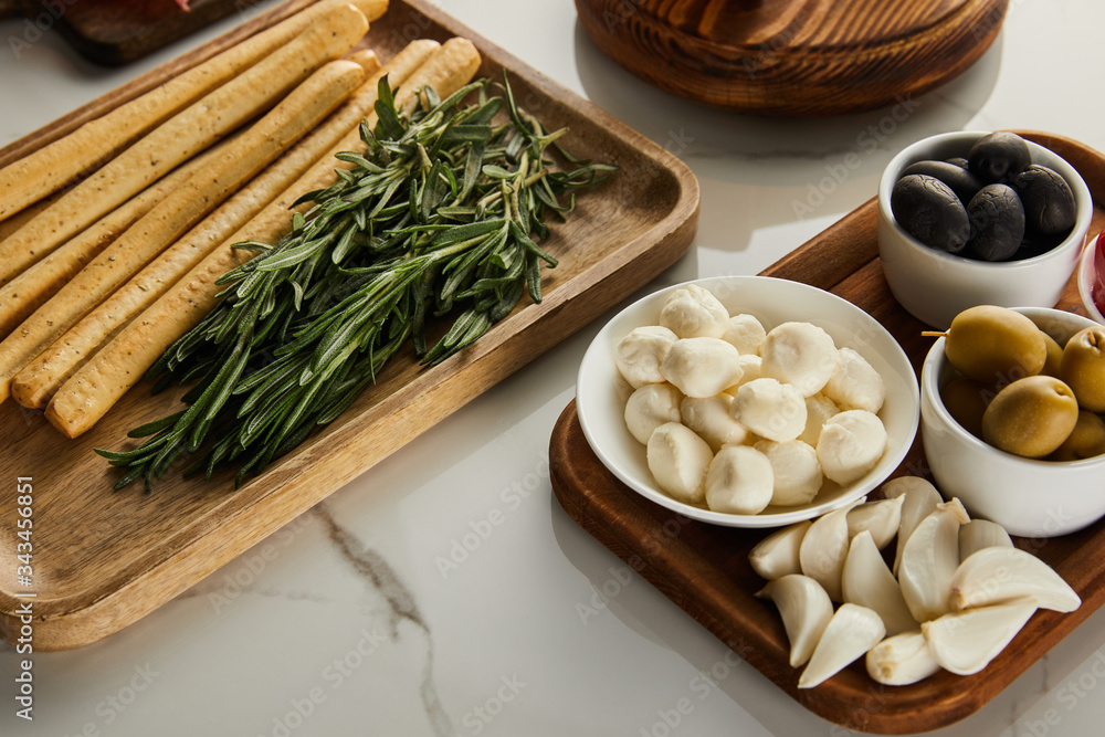 High angle view of boards with breadsticks, rosemary and antipasto ingredients on white background High angle view of boards with breadsticks, rosemary and antipasto ingredients on white background