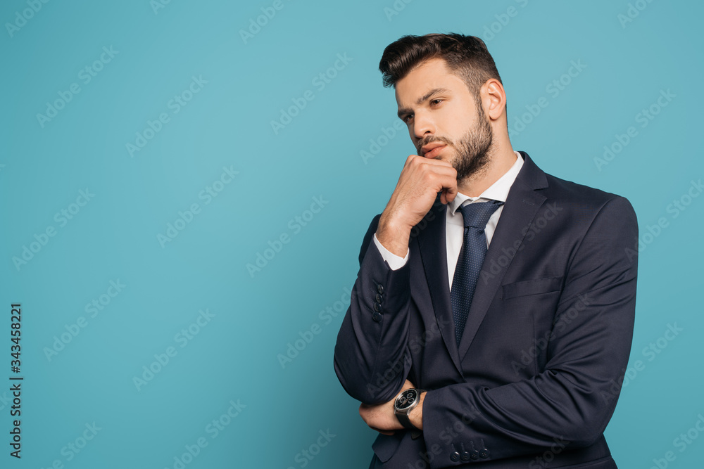 thoughtful businessman holding hand near face on blue background thoughtful businessman holding hand near face on blue background
