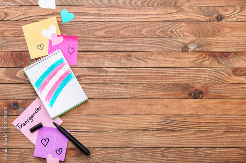 Notebook with drawing of transgender flag on wooden background