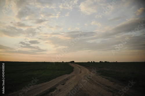 Fork of two country roads in the evening in the field. Evening landscape.