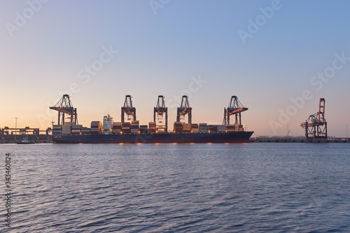 Huge container ships in port being loaded in Rotterdam in evening twiligt photo