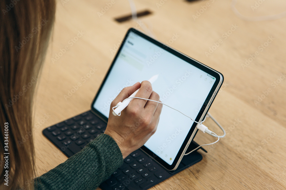 Turkey, Istanbul, December 17, 2019: sale New tablet APPLE iPad in the  official Apple store. The buyer is trying to draw a simple drawing with the  stylus on the gadget screen foto