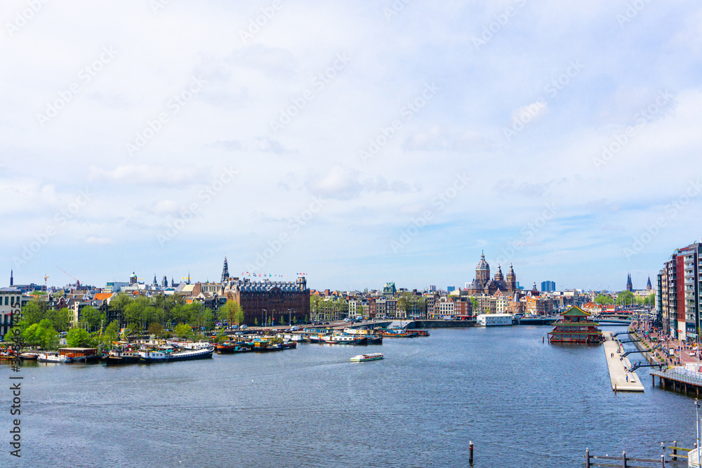 Fototapeta premium Typical canal in the center of Amsterdam. Visible are restaurants, sightseeing tourism boats at canal. Amsterdam, Netherlands.