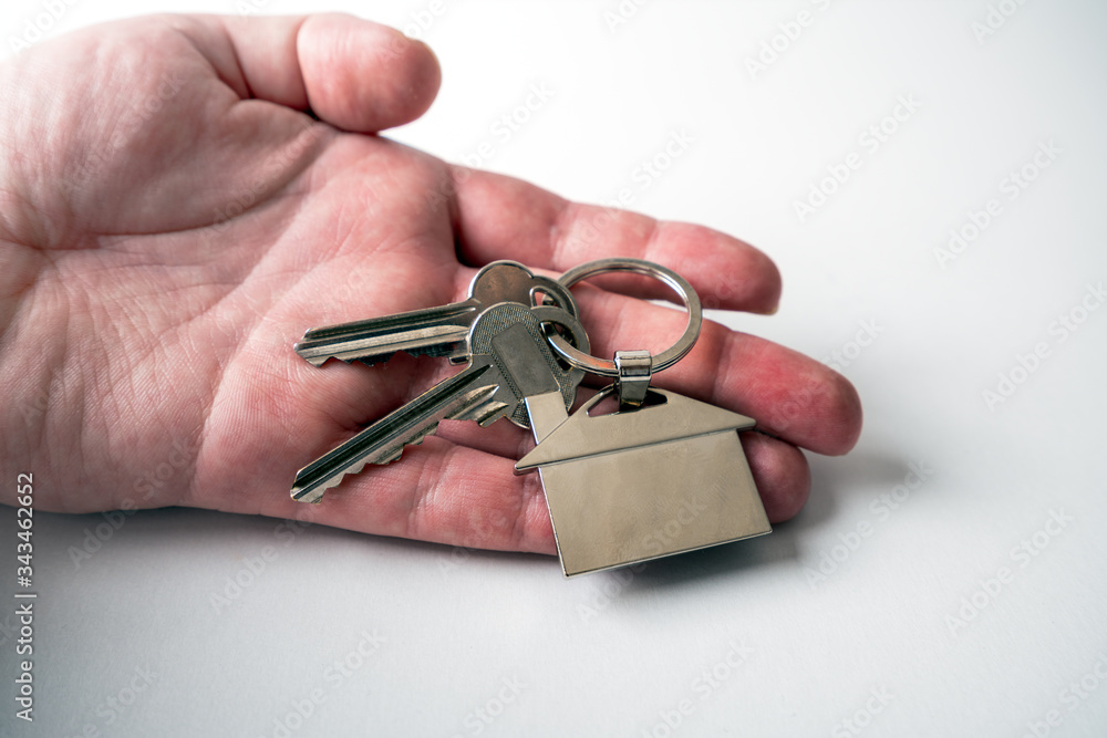 Hand holding house keys with house key chain isolated on white background, to illustrate the purchase of a new house, home rental or personal security concepts. Hand holding house keys with house key chain isolated on white background, to illustrate the purchase of a new house, home rental or personal security concepts.