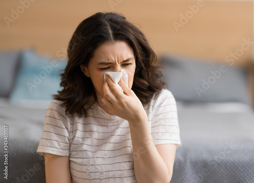 girl is holding paper tissue and blowing nose