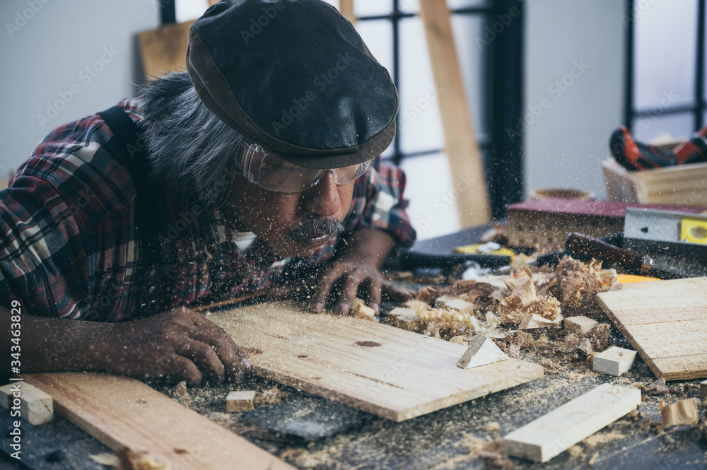 A carpenter is making crafts from wood. A carpenter is making crafts from wood.