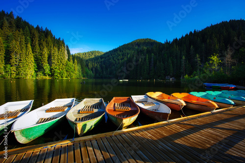Colorful small boats parked to wooden pier.