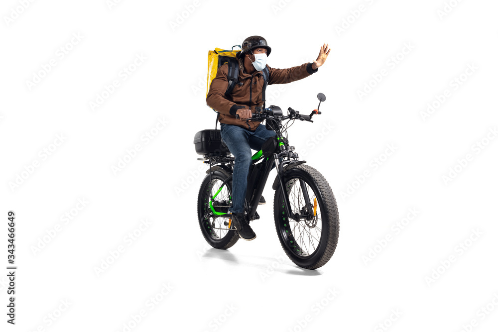 Obraz premium Too much orders. Contacless delivery service during quarantine. Man delivers food during isolation, wearing helmet and face mask. Taking food on bike isolated on white background. Safety. Hurrying up.