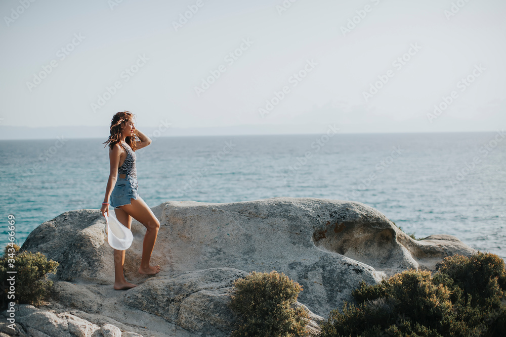 Young woman in bikini walking on rocks by the sea Young woman in bikini walking on rocks by the sea