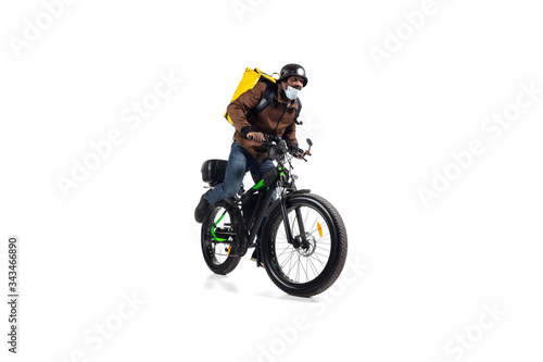 Too much orders. Contacless delivery service during quarantine. Man delivers food during isolation, wearing helmet and face mask. Taking food on bike isolated on white background. Safety. Hurrying up.