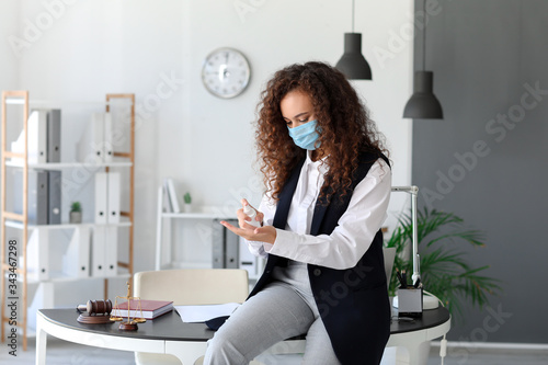 African-American businesswoman with disinfectant in office