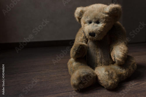 toy of a lonely teddy bear sits on a dark wooden floor