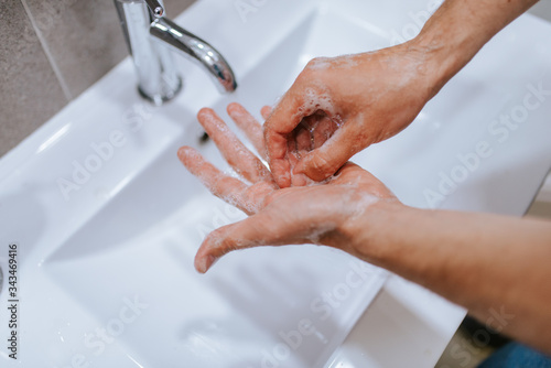 Close up of caucasian man washes his hands in the bathroom. COVID - 19 prevention