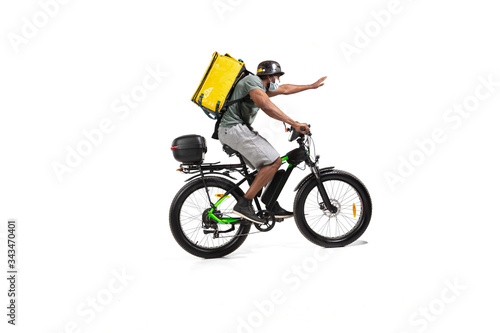 Fototapeta Naklejka Na Ścianę i Meble -  Too much orders. Contacless delivery service during quarantine. Man delivers food during isolation, wearing helmet and face mask. Taking food on bike isolated on white background. Safety. Hurrying up.