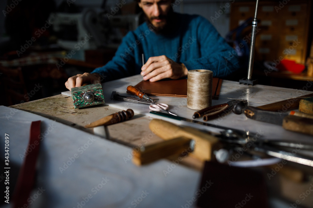 A leather craftsman works in a workshop. A leather craftsman works in a workshop.