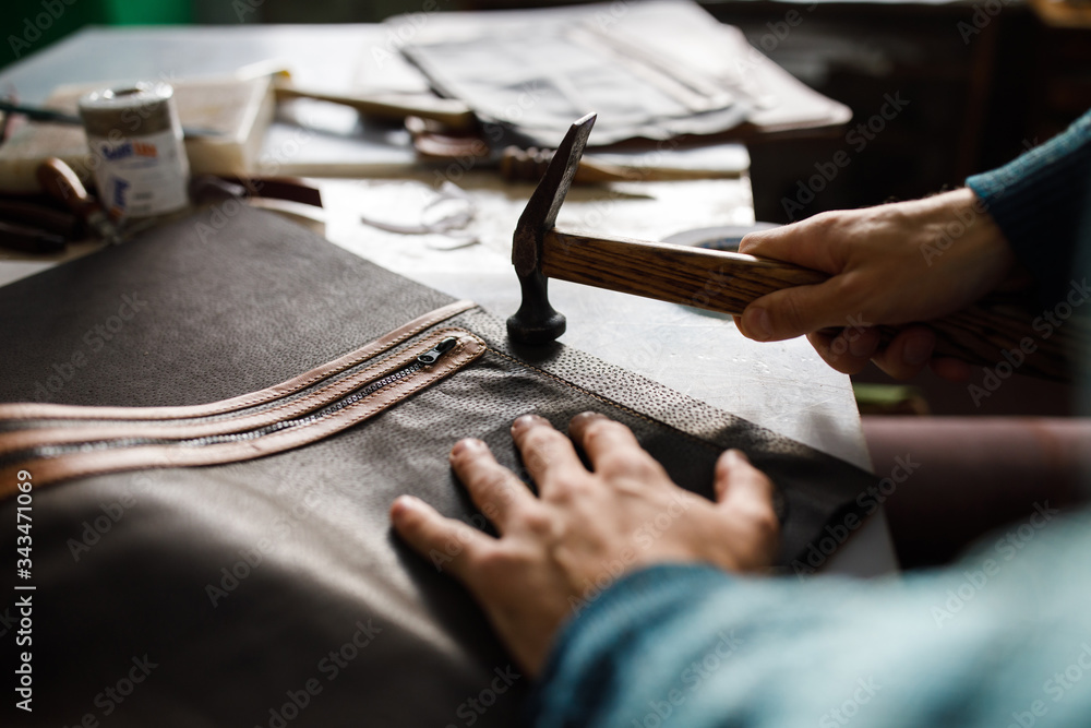 A leather craftsman works in a workshop. A leather craftsman works in a workshop.