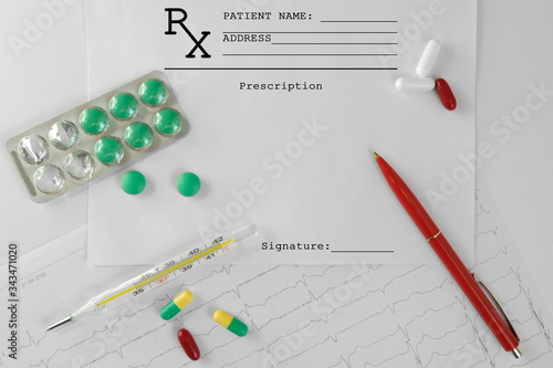 A clean prescription for the drug is next to scattered white, red, green, and yellow-green tablets, a cardiogram, a thermometer, and a red pen.