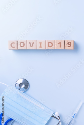 Fototapeta Naklejka Na Ścianę i Meble -  COVID-19 word wooden cube with mask, medical equipment, world disease pandemic infection and prevention concept, top view, flat lay, overhead design