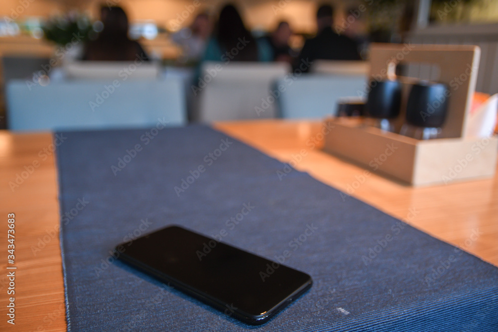 Cellphone on the table in cafe with beautiful blurred background Cellphone on the table in cafe with beautiful blurred background