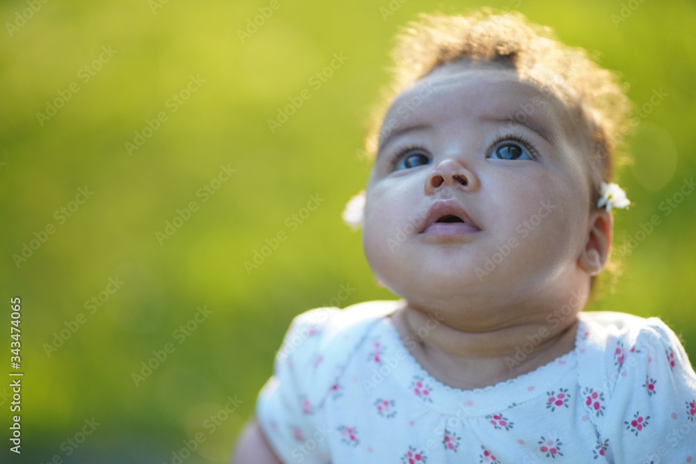 beautiful baby portrait looking up to the sky during sunset wearing 4 months to 6 month baby suit. Green grass backgrounds and sun that comes from the back of the baby. 85mm lens photography beautiful baby portrait looking up to the sky during sunset wearing 4 months to 6 month baby suit. Green grass backgrounds and sun that comes from the back of the baby. 85mm lens photography