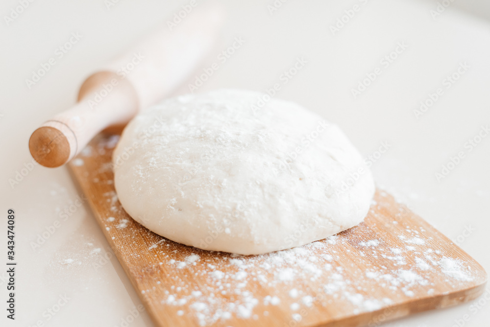 Raw dough a floured on a wooden cutting board. Food photography recipe idea. Pizza dough with rolling pin. Process of making homemade bread. Home bread baking. Raw dough a floured on a wooden cutting board. Food photography recipe idea. Pizza dough with rolling pin. Process of making homemade bread. Home bread baking.