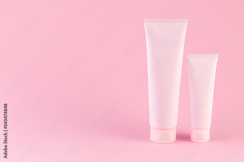 Two cosmetic tubes package on pastel pink background. Blank plastic containers, simple packaging design template. shallow depth of field, copy space photography. Two cosmetic tubes package on pastel pink background. Blank plastic containers, simple packaging design template. shallow depth of field, copy space photography.