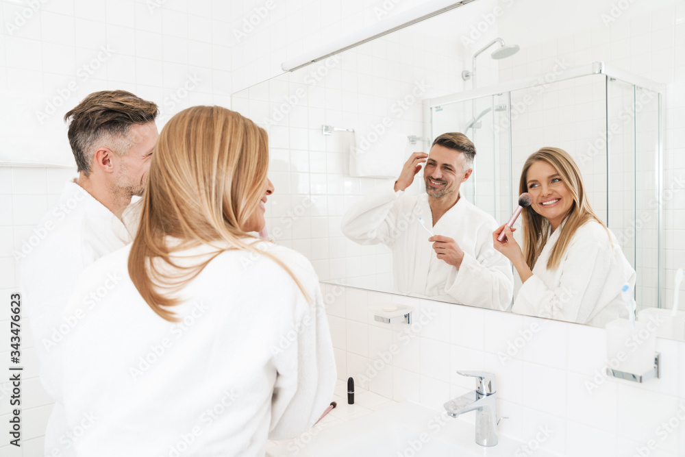 Fototapeta premium Photo of happy couple smiling and looking at mirror in bathroom