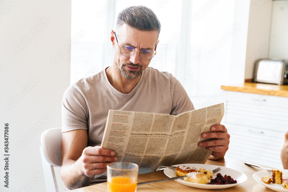 Photo of serious man reading newspaper while having breakfast Photo of serious man reading newspaper while having breakfast