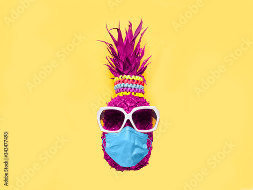 Pineapple in sunglasses and medical mask on a yellow background