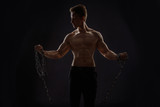 strong athletic man with chains on black background