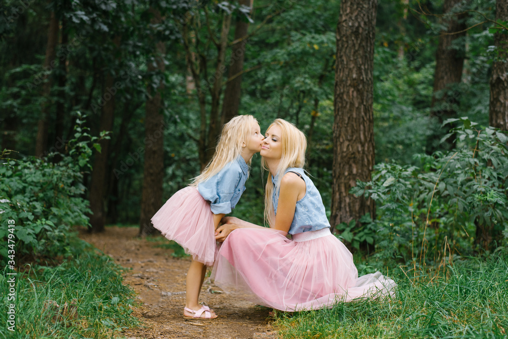 A mother and a five-year-old daughter in the same romantic clothes are walking in the Park or in the woods. My daughter kisses my mother on the cheek