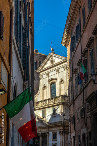 Spacer uliczkami Rzymu. Wiszące flagi narodowe i kościół w tle