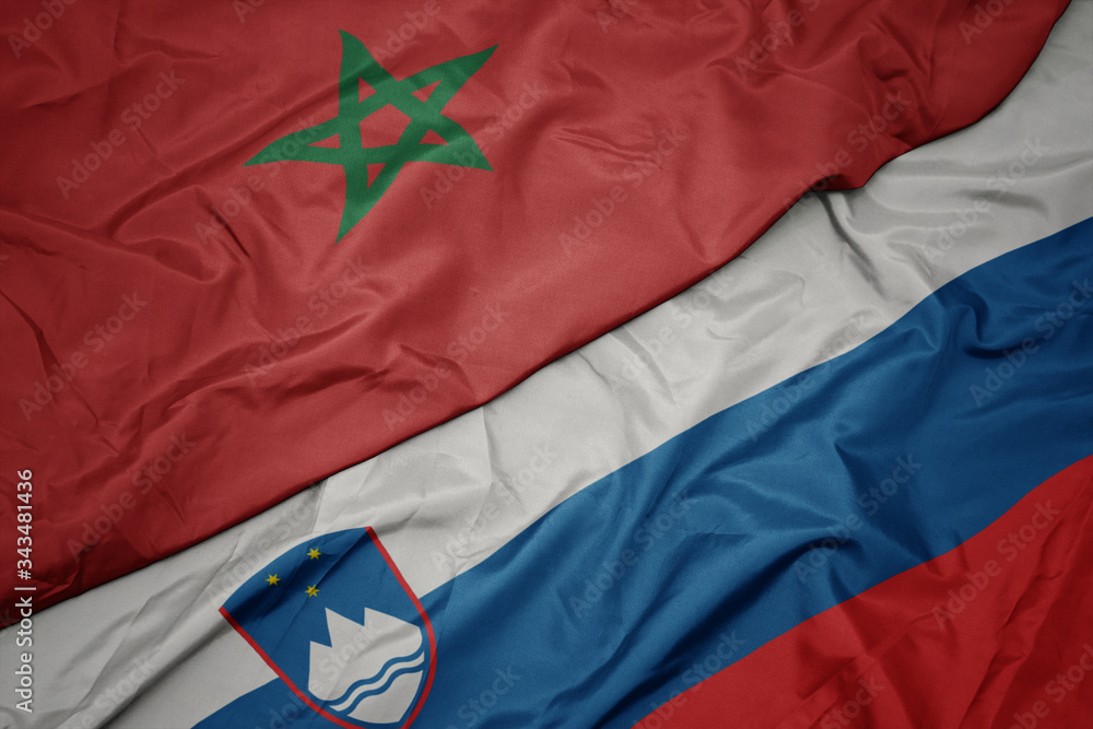 waving colorful flag of slovenia and national flag of morocco.