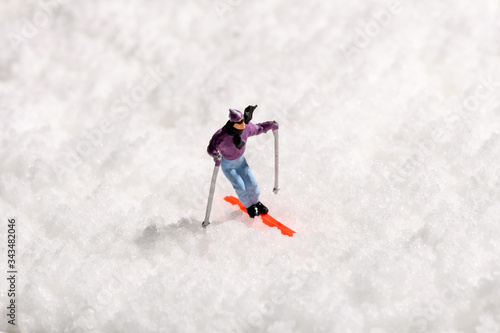 Lone miniature man skiing on fresh winter snow
