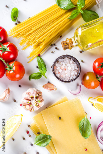 Italian food ingredients for cooking Spaghetti Pasta. Raw spaghetti pasta with various ingredient - onion, tomatoes, garlic, basil, parsley, cheese, olive oil. On white table background, flatlay copy