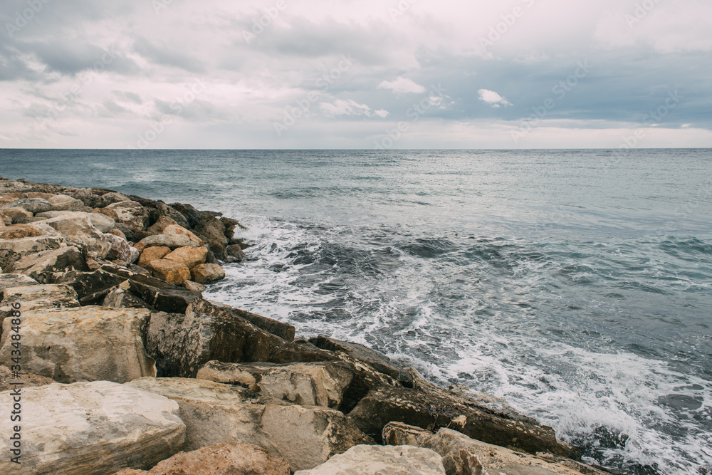 tranquil coastline with rocks near mediterranean sea against cloudy sky