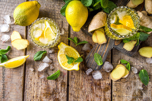 Homemade ginger lemonade cocktail. Cold summer ginger lemon ale. Sweet and sour iced refreshing beverage with lemon slice garnish, Detox and weight loss drink concept. Wooden rustic background copy s