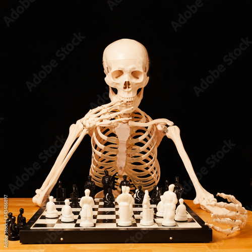 The skeleton plays chess at the table
