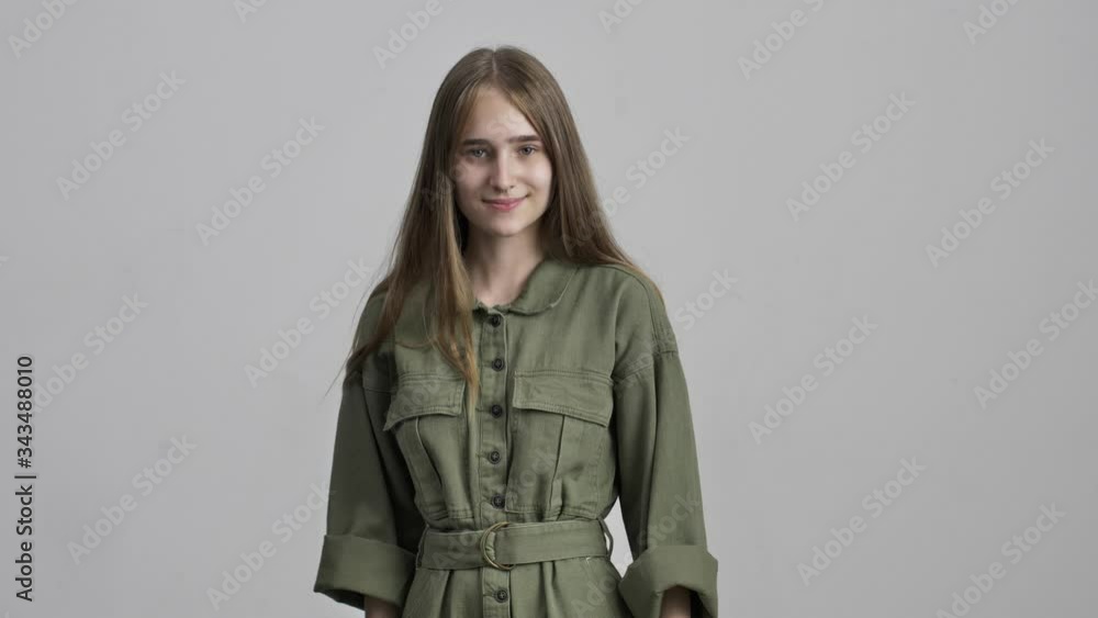Beautiful young positive girl posing isolated over grey wall background pointing to you Beautiful young positive girl posing isolated over grey wall background pointing to you