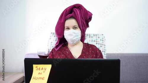 Girl after a shower, drinking wine and working on a laptop. Covid 19