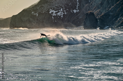Surfer wipeout with waves and spray background. Aerial view of surfer falling off surf board at sunset.
