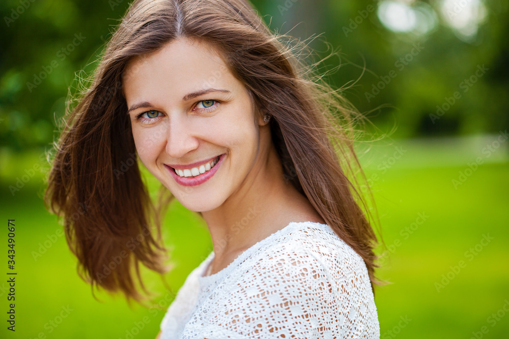 Naklejka premium Close up portrait of beautiful young happy brunette woman with fresh and clean skin, summer street outdoors