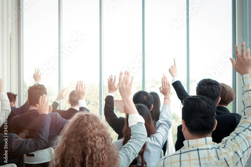 Business people raising hand up to ask question with speaker in seminar conference, raise hands up to agree or vote for comments in the meeting