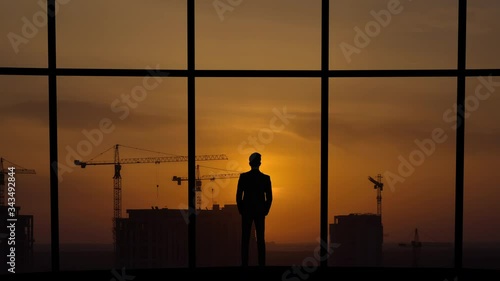 The man stands near a panoramic window against a building